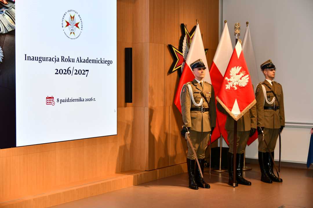 Poczet sztandarowy. Trzech żołnierzy z szablami. Obok nich wyświetlony slajd z napisem Inauguracja Roku Akademickiego 2026/2027.