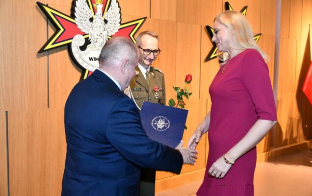 Alojzy Nowak i Grzegorz Gielerak wręczają pracowniczce WIM dyplom.