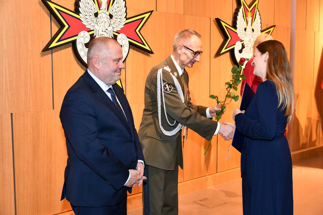 Alojzy Nowak i Grzegorz Gielerak wręczają pracowniczce WIM dyplom.