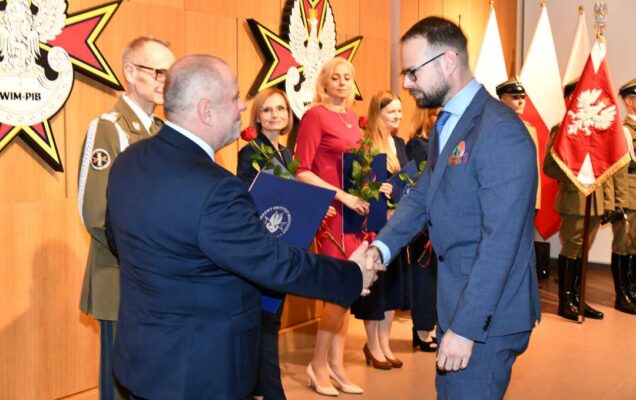 Alojzy Nowak i Grzegorz Gielerak wręczają pracownikowi WIM dyplom.