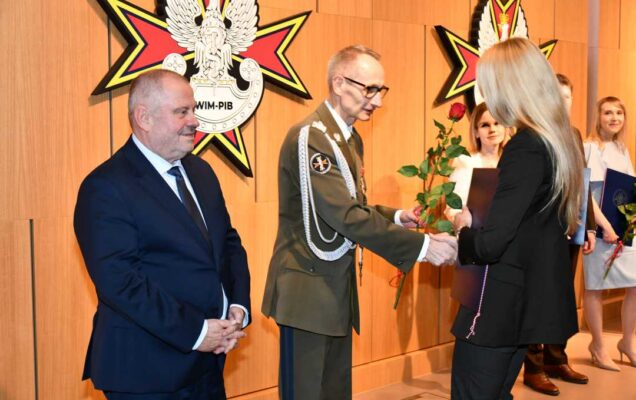 Alojzy Nowak i Grzegorz Gielerak wręczają pracowniczce WIM dyplom.