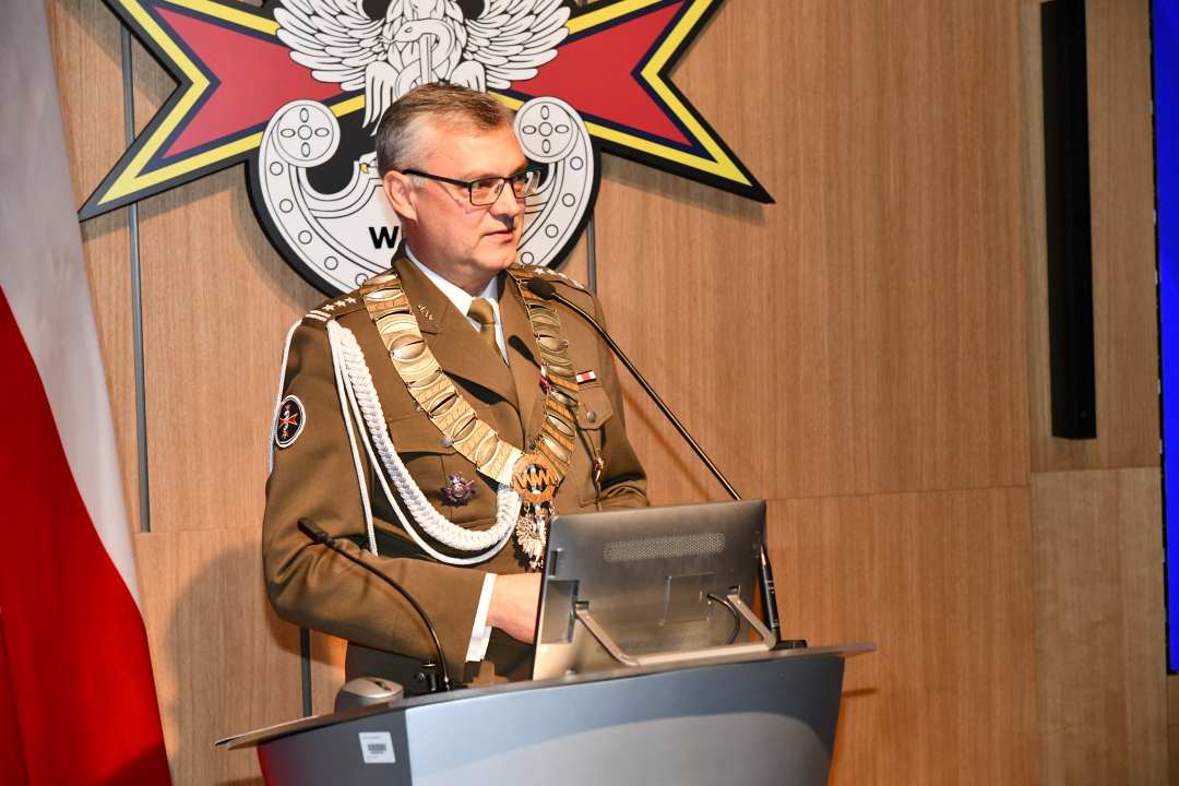 Marek Saracyn przy mównicy. Za nim flaga Polski i logotyp WIM-PIB.